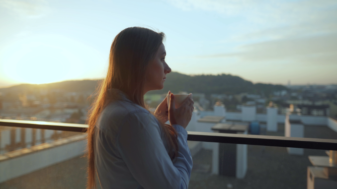 a woman stood on a balcony holding coffee