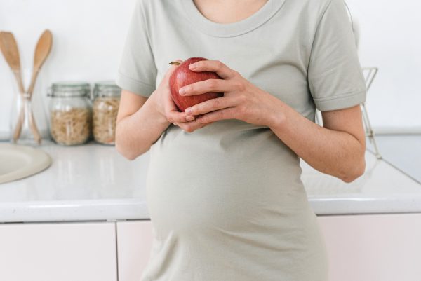 Image of a pregnant woman holding an apple for Mindful Mamas sessions